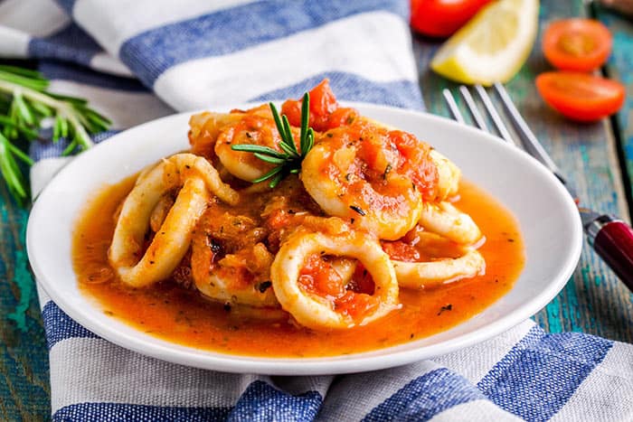  squid onions served on a plate dipped in sauce 